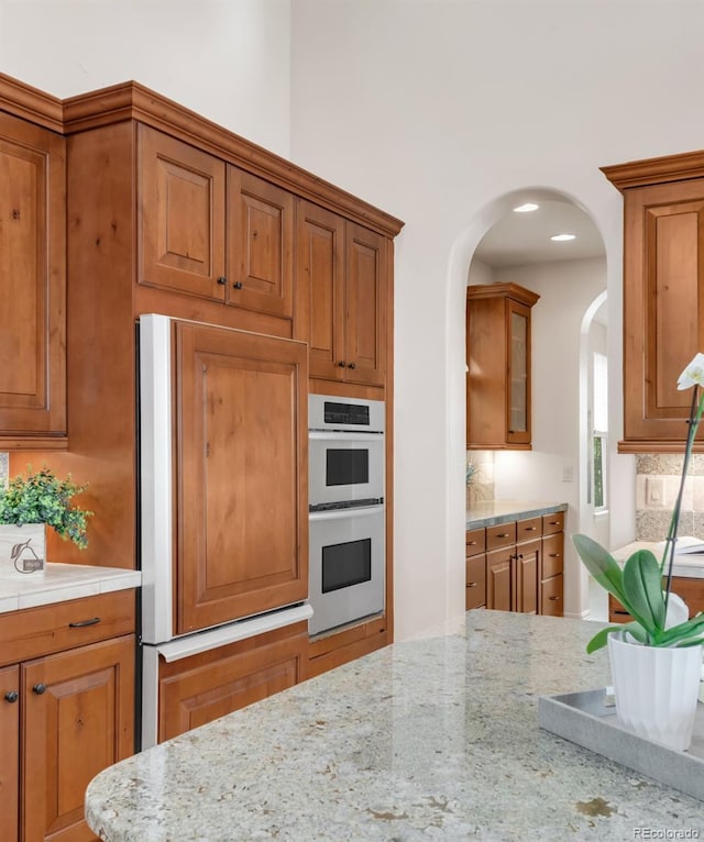 3143 Elmira St, Denver, CO 80238 - kitchen with double oven, paneled built in fridge, tasteful backsplash, and brown cabinets