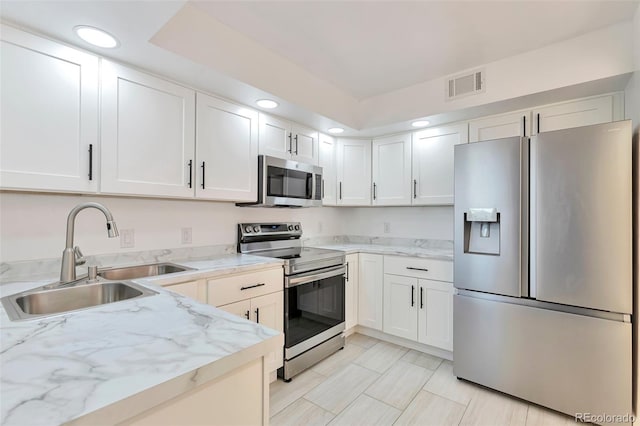 kitchen featuring light stone countertops, stainless steel appliances, white cabinetry, and sink