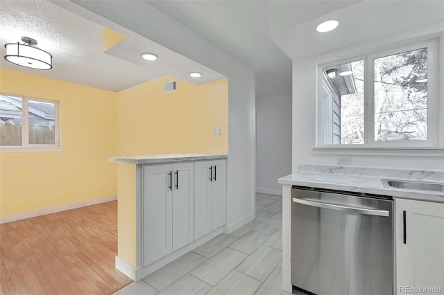 kitchen featuring white cabinetry, stainless steel dishwasher, a wealth of natural light, and light hardwood / wood-style floors