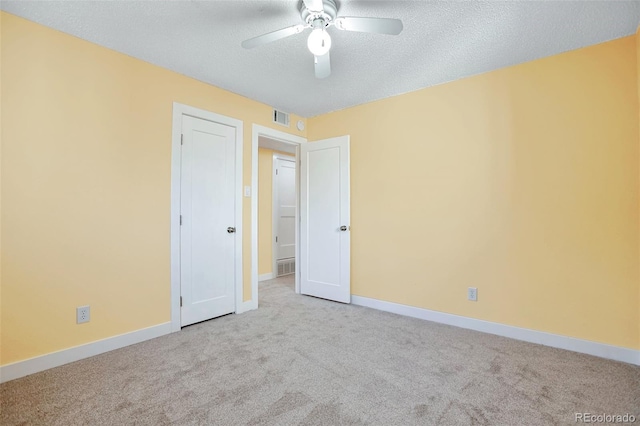 spare room with ceiling fan, a textured ceiling, and light carpet