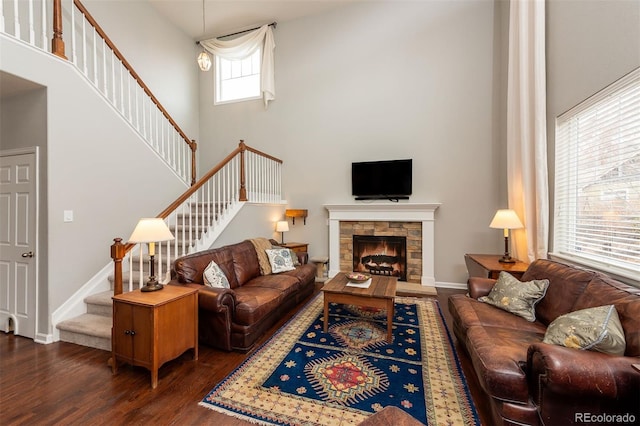 living room featuring a fireplace, a towering ceiling, baseboards, stairway, and dark wood-style floors