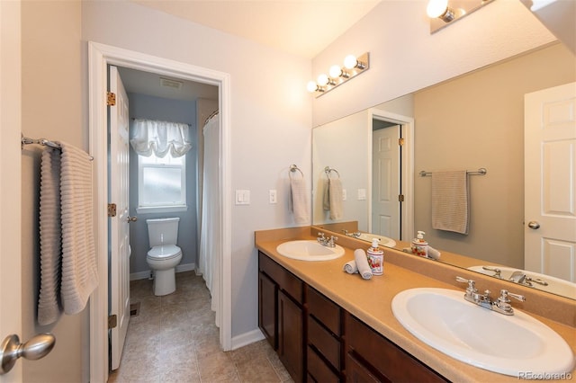 bathroom featuring double vanity, visible vents, toilet, and a sink