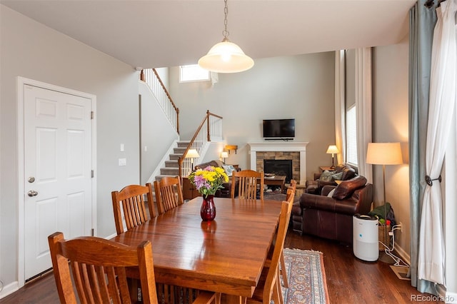 dining room featuring stairway, a fireplace, and wood finished floors