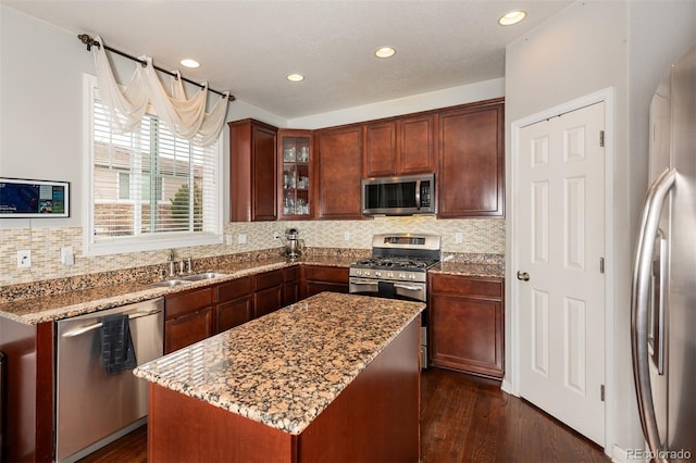 kitchen with glass insert cabinets, appliances with stainless steel finishes, dark wood-type flooring, and light stone counters