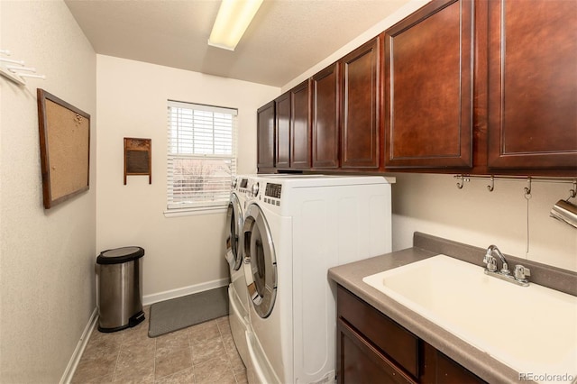 washroom featuring light tile patterned floors, washing machine and dryer, a sink, baseboards, and cabinet space