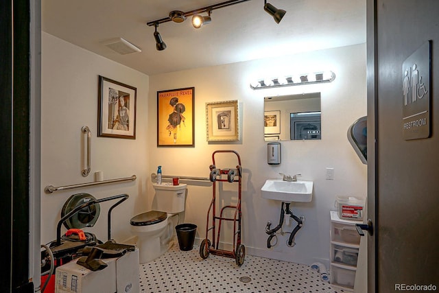 interior space with sink, track lighting, and toilet