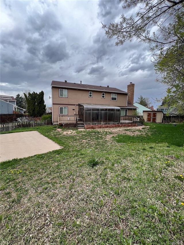 rear view of property featuring a patio, a storage shed, and a lawn