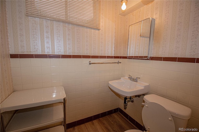 bathroom featuring sink, wood-type flooring, tile walls, and toilet