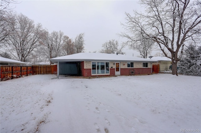 snow covered property featuring brick siding and a fenced backyard