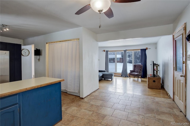 kitchen featuring ceiling fan, blue cabinets, open floor plan, light countertops, and stainless steel refrigerator