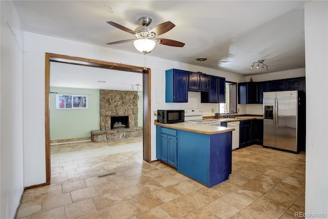 kitchen with white appliances, light countertops, a peninsula, and blue cabinetry