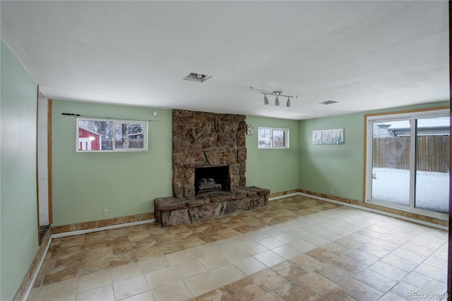 unfurnished living room with a fireplace, plenty of natural light, and baseboards