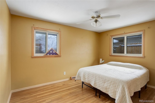 bedroom with ceiling fan, light wood-style floors, and baseboards