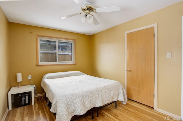 bedroom with a ceiling fan, baseboards, and wood finished floors