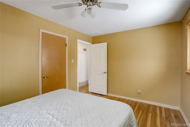 bedroom featuring baseboards, visible vents, ceiling fan, and light wood finished floors