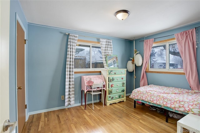 bedroom featuring multiple windows, wood finished floors, and baseboards