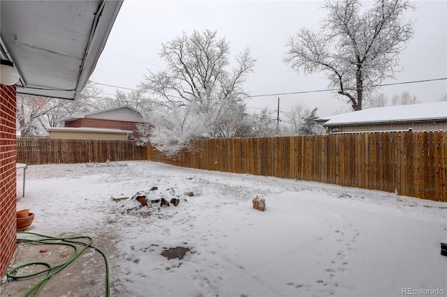 snowy yard featuring a fenced backyard