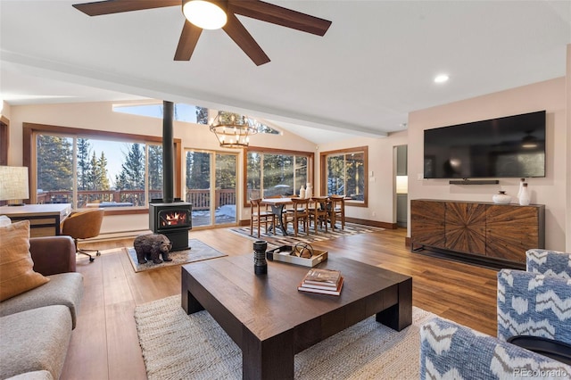 living room featuring baseboards, lofted ceiling, wood finished floors, a wood stove, and recessed lighting