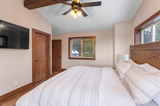 bedroom with vaulted ceiling with beams, a ceiling fan, baseboards, and wood finished floors