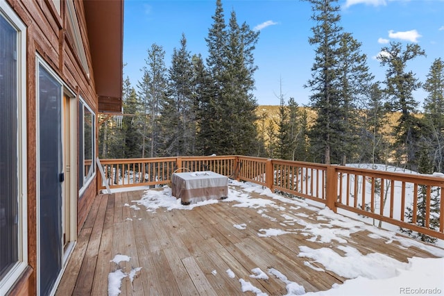 snow covered deck with a wooded view