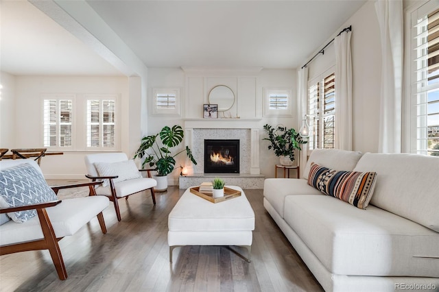 living area with a glass covered fireplace, a wealth of natural light, and wood finished floors