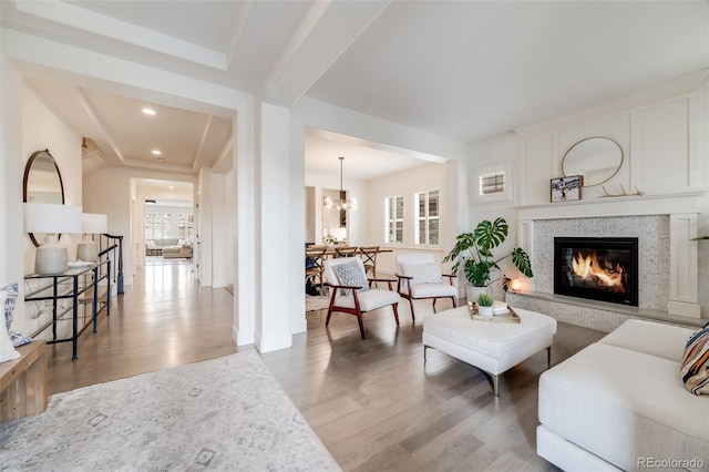 living area with a notable chandelier, a fireplace, wood finished floors, and recessed lighting