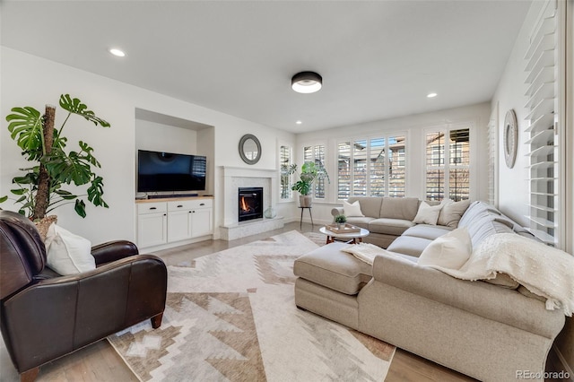 living area featuring a fireplace, light wood-style flooring, and recessed lighting