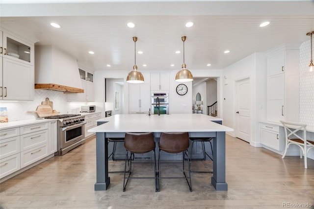 kitchen with stainless steel appliances, arched walkways, premium range hood, and a breakfast bar