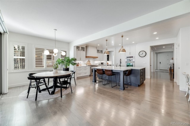 dining area featuring baseboards, recessed lighting, an inviting chandelier, and light wood-style floors