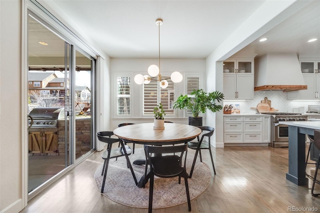 dining space with light wood-type flooring, baseboards, and a notable chandelier