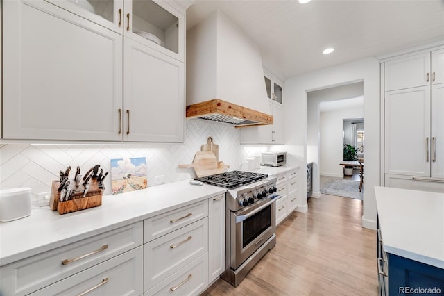 kitchen with white cabinets, custom range hood, high end range, and light countertops