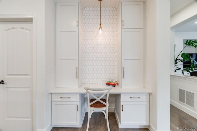 office space featuring dark wood-style flooring, visible vents, built in desk, and baseboards