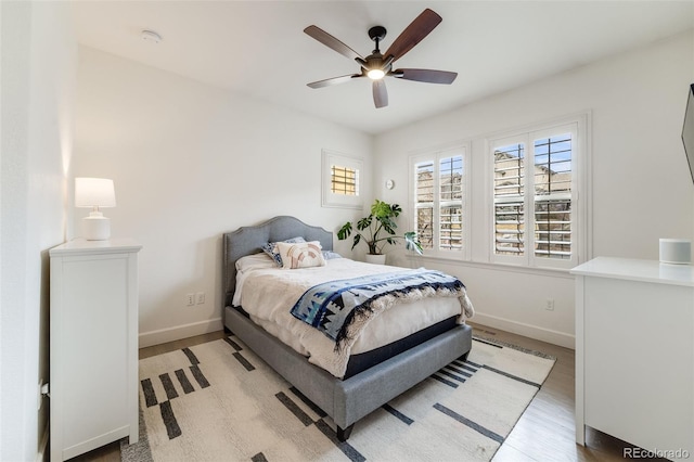 bedroom featuring a ceiling fan, light wood-type flooring, and baseboards