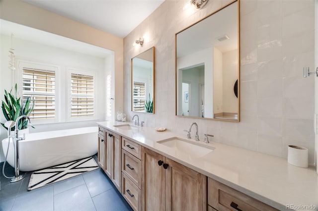 bathroom featuring double vanity, a sink, a freestanding bath, and tile patterned floors