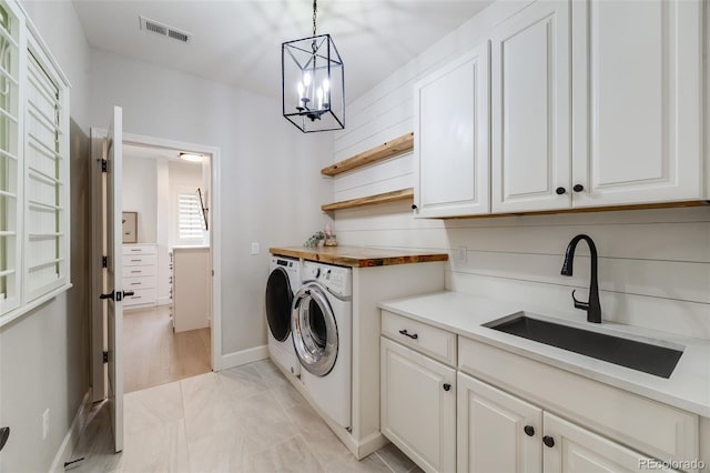 laundry area with cabinet space, visible vents, a sink, a chandelier, and independent washer and dryer