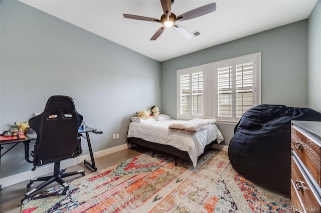 bedroom featuring visible vents, baseboards, a ceiling fan, wood finished floors, and vaulted ceiling