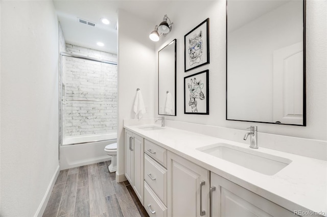 full bathroom featuring toilet, wood finish floors, a sink, and visible vents