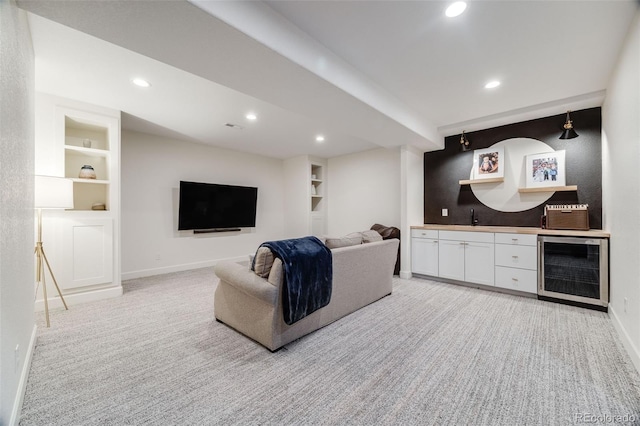 living area featuring light carpet, beverage cooler, built in shelves, and baseboards