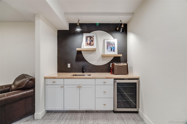 bar with wine cooler, indoor wet bar, a sink, and baseboards