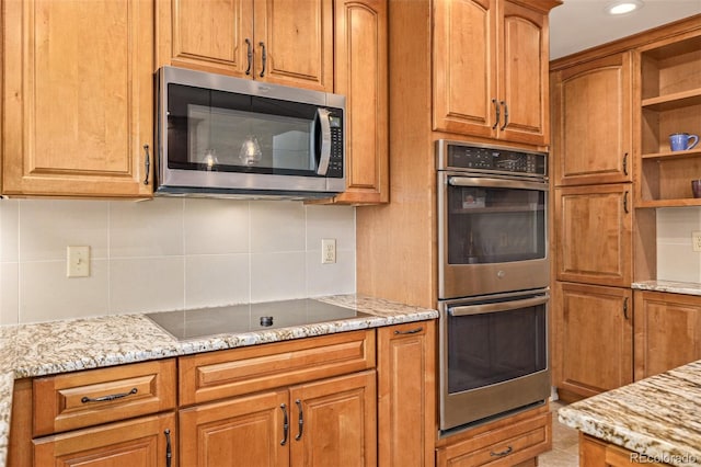 kitchen featuring appliances with stainless steel finishes, backsplash, and light stone counters