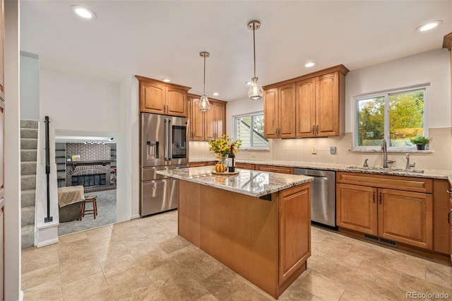 kitchen with pendant lighting, sink, a center island, light stone counters, and stainless steel appliances