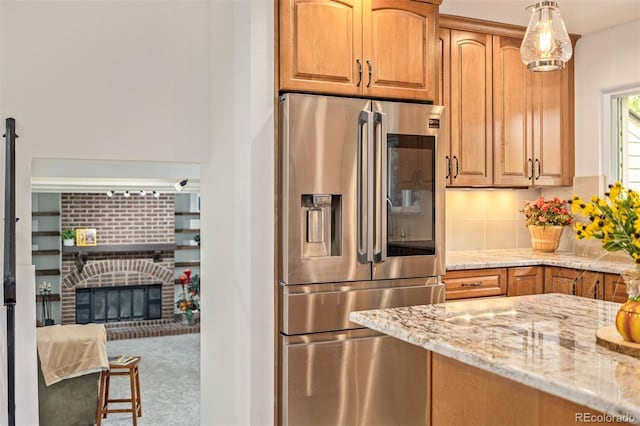 kitchen featuring light stone counters, stainless steel fridge, carpet, and hanging light fixtures