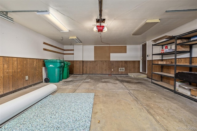 garage with a garage door opener and wooden walls