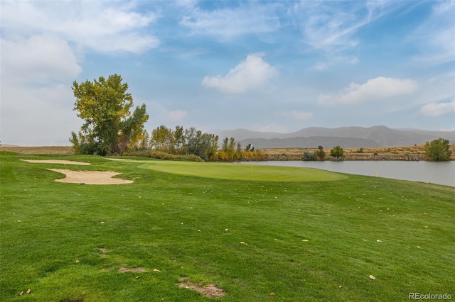 view of property's community with a water and mountain view and a lawn