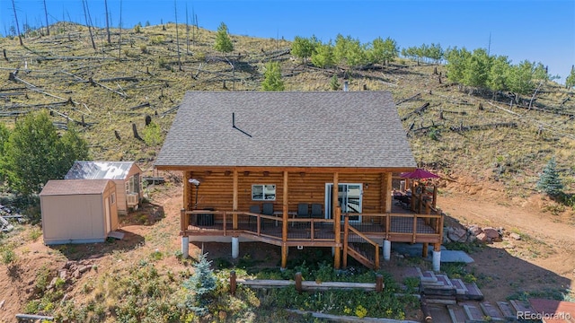 14077 S State Highway 67, Woodland Park, CO 80863 - rear view of property with log exterior, a shed, an outdoor structure, a shingled roof, and a deck