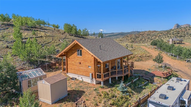 14077 S State Highway 67, Woodland Park, CO 80863 - view of property exterior with an outbuilding, a shed, roof with shingles, log exterior, and a deck with mountain view
