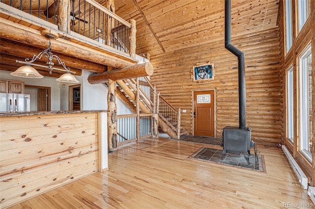 14077 S State Highway 67, Woodland Park, CO 80863 - unfurnished living room with rustic walls, a wood stove, a towering ceiling, baseboard heating, and hardwood / wood-style flooring