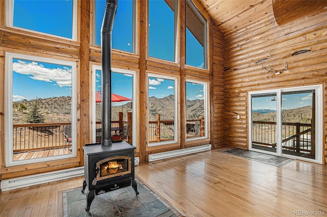 14077 S State Highway 67, Woodland Park, CO 80863 - living area featuring a baseboard radiator, a wood stove, high vaulted ceiling, log walls, and a mountain view