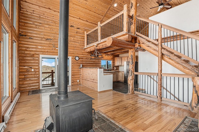 14077 S State Highway 67, Woodland Park, CO 80863 - unfurnished living room with a wood stove, high vaulted ceiling, log walls, wooden ceiling, and a baseboard heating unit