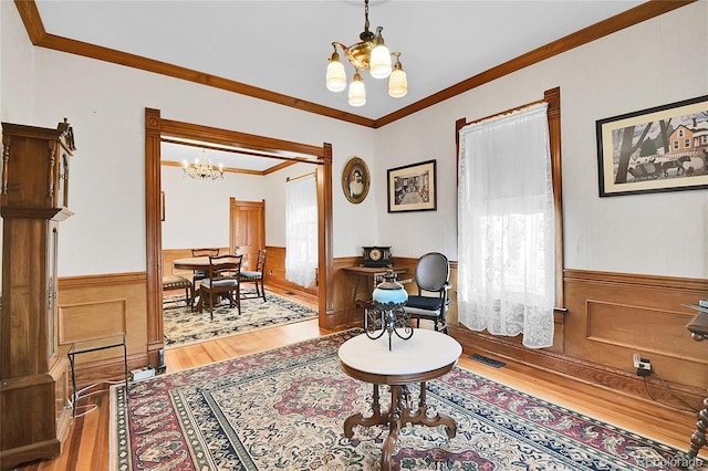 interior space with visible vents, an inviting chandelier, ornamental molding, light wood-style floors, and wainscoting